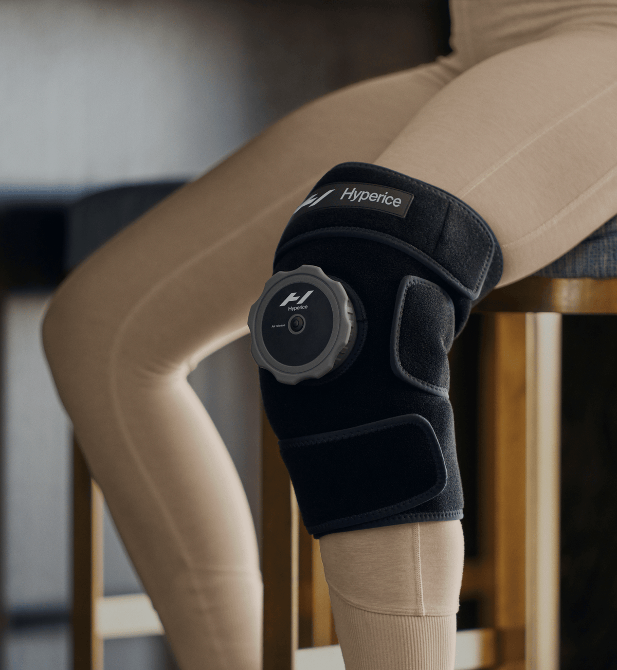 Person sitting with the Hyperice Knee ice compression wrap on the knee