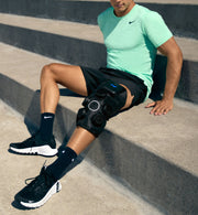 Person wearing a hyperice x 2 knee device sitting on concrete steps