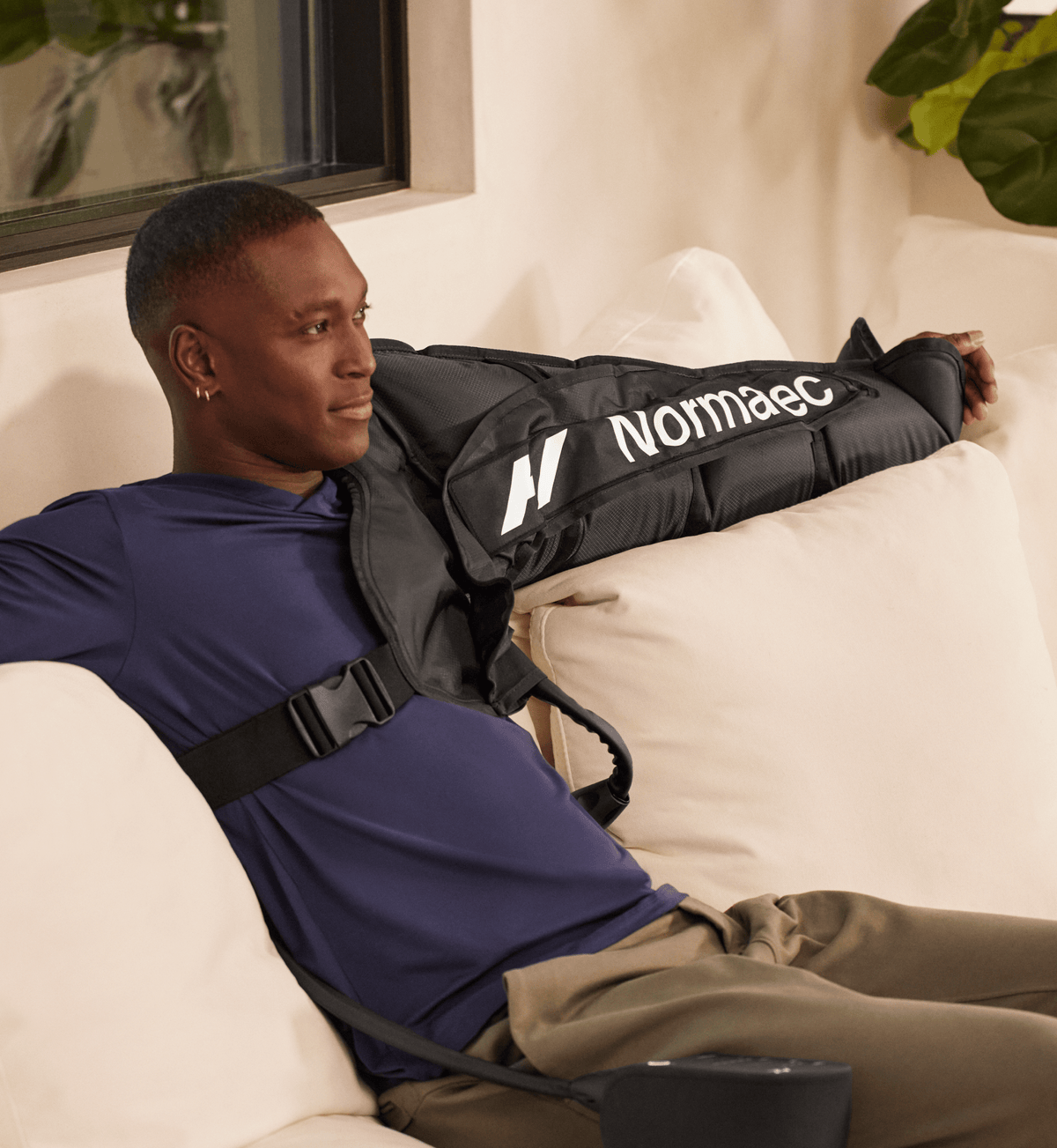 Mies sohvalla Normatec Arm Attachments -käsiosat käsissään